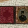 An ambrotype portrait of cadet Dabney Scales in US Naval Academy uniform, Maryland, c 1859-60, housed in its original hinge-split case, on top of Scales' Shenandoah diary, 1865