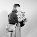 Young woman, standing, wearing pleated skirt, holding pile of books, 1966. Photo by Mark Strizic. This work is in copyright. H2009.81/4079
